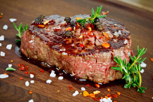 grilled steak with thyme on wooden board